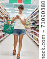 Woman in supermarket checking shopping list on smartphone 71090380
