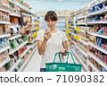 Woman using mobile phone while shopping in supermarket 71090382