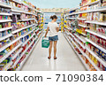 Woman shopping in a supermarket looking at the screen of the phone her shopping list 71090384