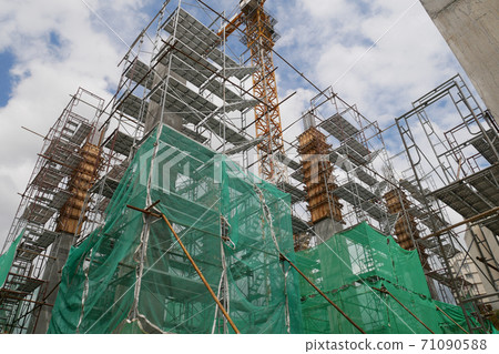 SHAH ALAM, MALAYSIA -AUGUST 6, 2020: Temporary staircase and scaffolding are used in the construction of high concrete columns. Scaffolding is wrapped with safety netting for safety purposes. Installe 71090588