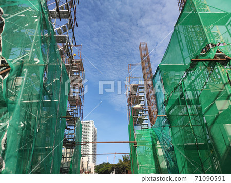 SHAH ALAM, MALAYSIA -AUGUST 6, 2020: Temporary staircase and scaffolding are used in the construction of high concrete columns. Scaffolding is wrapped with safety netting for safety purposes. Installe SHAH ALAM, MALAYSIA -AUGUST 6, 2020: Temporary staircase and scaffolding are used in the construction of high concrete columns. Scaffolding is wrapped with safety netting for safety purposes. Installe 71090591