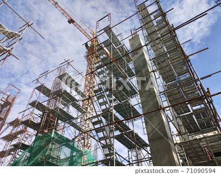 SHAH ALAM, MALAYSIA -AUGUST 6, 2020: Temporary staircase and scaffolding are used in the construction of high concrete columns. Scaffolding is wrapped with safety netting for safety purposes. Installe SHAH ALAM, MALAYSIA -AUGUST 6, 2020: Temporary staircase and scaffolding are used in the construction of high concrete columns. Scaffolding is wrapped with safety netting for safety purposes. Installe 71090594