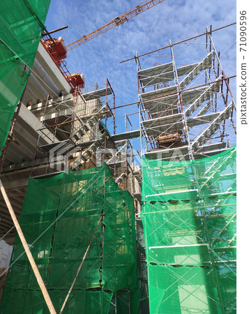 SHAH ALAM, MALAYSIA -AUGUST 6, 2020: Temporary staircase and scaffolding are used in the construction of high concrete columns. Scaffolding is wrapped with safety netting for safety purposes. Installe SHAH ALAM, MALAYSIA -AUGUST 6, 2020: Temporary staircase and scaffolding are used in the construction of high concrete columns. Scaffolding is wrapped with safety netting for safety purposes. Installe 71090596