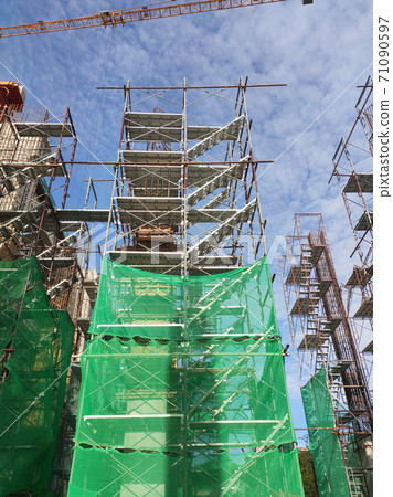 SHAH ALAM, MALAYSIA -AUGUST 6, 2020: Temporary staircase and scaffolding are used in the construction of high concrete columns. Scaffolding is wrapped with safety netting for safety purposes. Installe 71090597