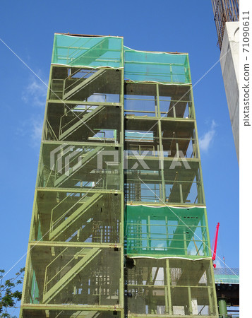 SHAH ALAM, MALAYSIA -AUGUST 6, 2020: Temporary staircase and scaffolding are used in the construction of high concrete columns. Scaffolding is wrapped with safety netting for safety purposes. Installe 71090611