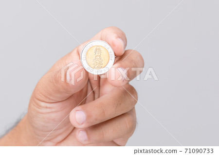 Hand holding Thailand coin (10 baht). Studio shot on grey background Hand holding Thailand coin (10 baht). Studio shot on grey background 71090733