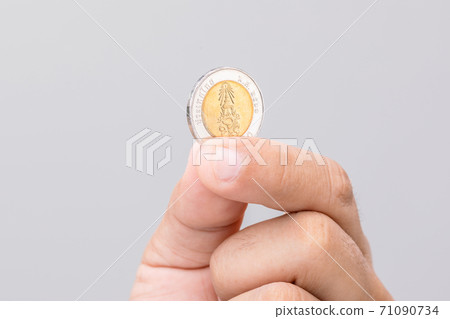 Hand holding Thailand coin (10 baht). Studio shot on grey background Hand holding Thailand coin (10 baht). Studio shot on grey background 71090734