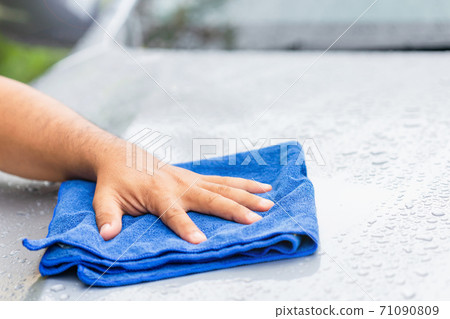 Hand holding blue cloth to cleaning wet body of modern car. Outdoor shooting in raining day. Hand holding blue cloth to cleaning wet body of modern car. Outdoor shooting in raining day. 71090809