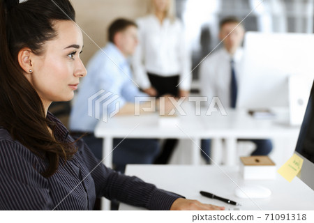 Business woman using computer at workplace in modern office. Brunette secretary or female lawyer looking at the camera and happy smiling. Working for pleasure and success Business woman using computer at workplace in modern office. Brunette secretary or female lawyer looking at the camera and happy smiling. Working for pleasure and success 71091318