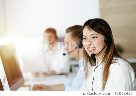 Asian woman working at customer service office. Business concept. Group of diverse operators at work in sunny call center. 71091453