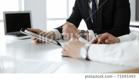 Unknown business people using tablet computer in modern office. Businessman or male entrepreneur is working with his colleague at the desk 71091493