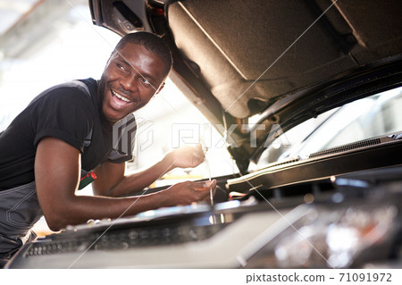 cheerful smiling afro man enjoy repairing car's hood 71091972