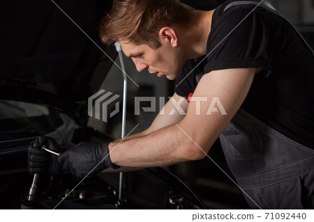repairing in action. hardworking guy employee in uniform works in the automobile salon repairing in action. hardworking guy employee in uniform works in the automobile salon 71092440