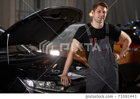 portrait of confident mechanic in uniform posing at camera in auto service 71092443