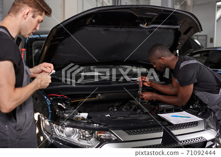 multi-ethnic team of african and caucasian men working in auto service multi-ethnic team of african and caucasian men working in auto service 71092444