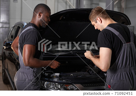 multi-ethnic team of african and caucasian men working in auto service multi-ethnic team of african and caucasian men working in auto service 71092451