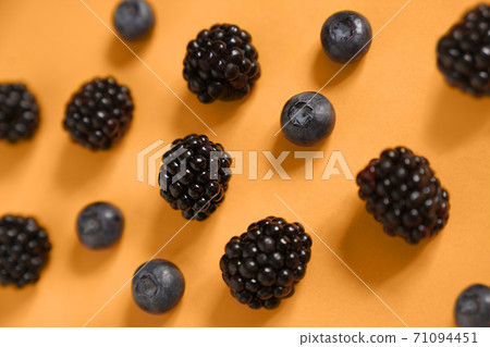 blackberries and blueberries on an orange background blackberries and blueberries on an orange background 71094451