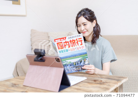 做旅行計劃的一個少婦在計算機上，當看小冊子時 71094477