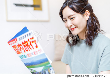 做旅行計劃的一個少婦在計算機上，當看小冊子時 71094478