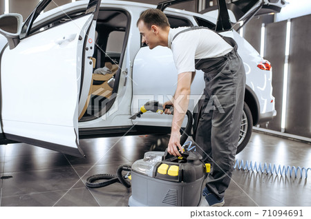 Worker with vacuum cleaner, car dry cleaning 71094691