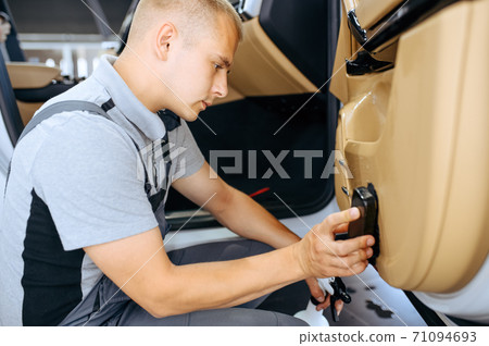 Worker with brush wipes car door trim, detailing 71094693