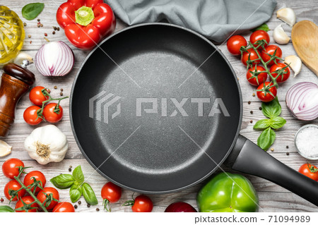 Top view of empty frying pan with vegetables on wooden table Top view of empty frying pan with vegetables on wooden table 71094989