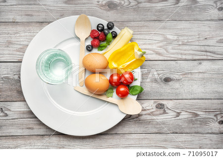Interval fasting diet concept represented with a plate and products 71095017