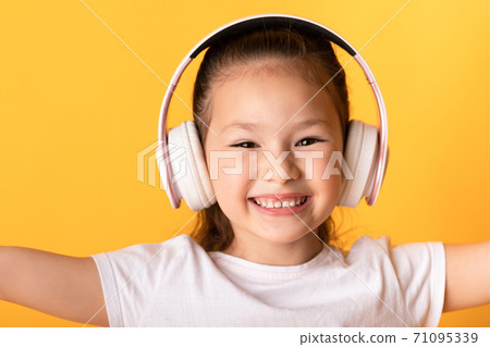 Smiling asian girl enjoying music using headset Smiling asian girl enjoying music using headset 71095339
