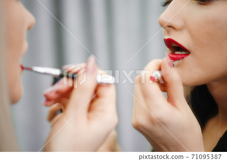 Close up view of woman applying lipstick looking to the mirror 71095387