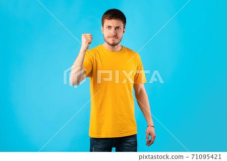 Young handsome man shaking clenched fist to camera Young handsome man shaking clenched fist to camera 71095421