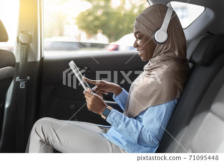 In Car Entertainment. Black Muslim Woman Using Digital Tablet While Riding Automobile 71095448
