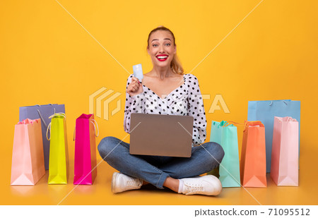 Happy woman with shopping bags, laptop and plastic card 71095512