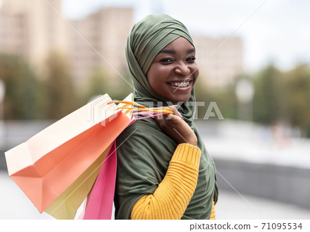 Shopping Lover. Happy Black Muslim Lady Carrying Shopper Bags While Walking Outdoors Shopping Lover. Happy Black Muslim Lady Carrying Shopper Bags While Walking Outdoors 71095534