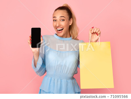 Excited lady showing black phone screen and shopping bag 71095566