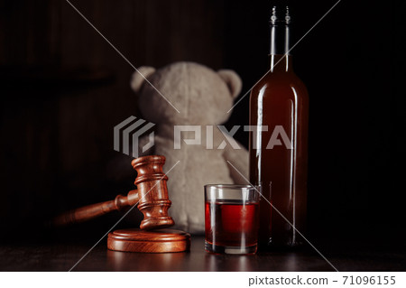 Alcohol in family and child abuse concept. Teddy bear as a symbol of child's safety, gavel and bottle with glass 71096155