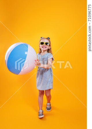 Funny happy child in sunglasses holding beachball on yellow background 71096775