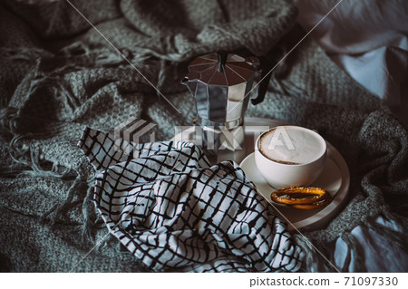 Cup of coffee on tray in cozy winter bad with wool blanket 71097330
