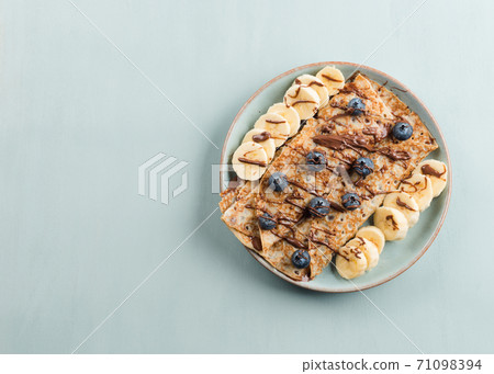 Crepes with chocolate nut spread, banana, berries 71098394