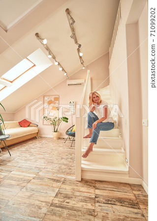 Pretty middle aged caucasian woman sitting on stairs Pretty middle aged caucasian woman sitting on stairs 71099202