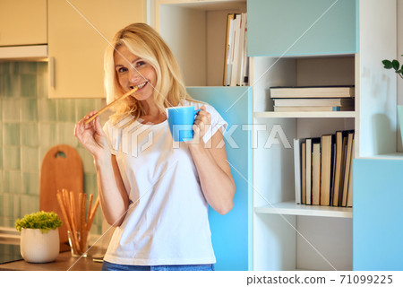 Happy middle aged woman with snack and coffee 71099225