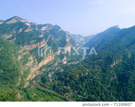 Aerial view of green mountain peak with beautiful blue sky. Aerial view of green mountain peak with beautiful blue sky. 71100607