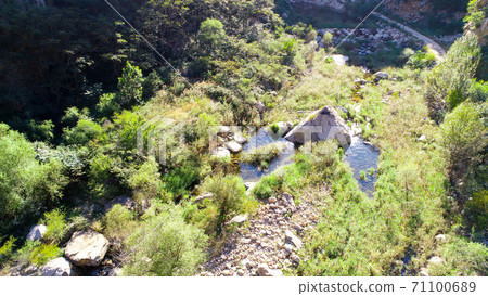 Aerial view of small river running in the forest next to mountain Aerial view of small river running in the forest next to mountain 71100689