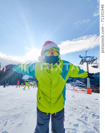 happy man in ski outfit with santa red christmas hat at winter mountains hill happy man in ski outfit with santa red christmas hat at winter mountains hill 71101946