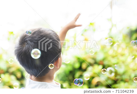 一個孩子伸手去拿一個沙邦球到外面的天空 71104239