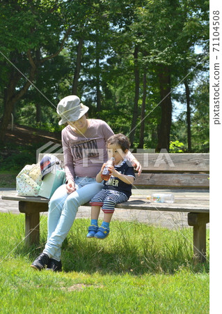 Parents and children resting on a bench in a lush park 71104508