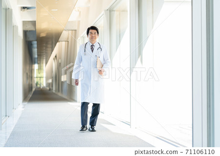 Middle-aged doctor walking in the hospital corridor Middle-aged doctor walking in the hospital corridor 71106110