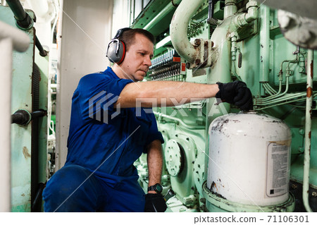 Marine engineer officer controlling vessel enginesand propulsion in engine control room ECR 71106301