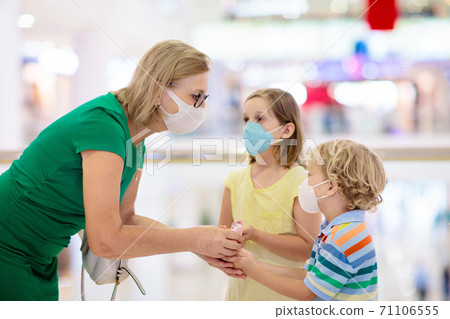 Mother and child with face mask and hand sanitizer 71106555