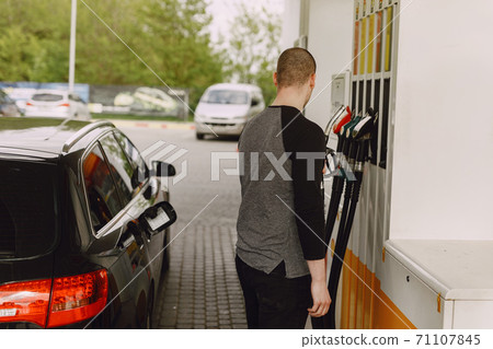 Handsome man pours gasoline into tank of car Handsome man pours gasoline into tank of car 71107845