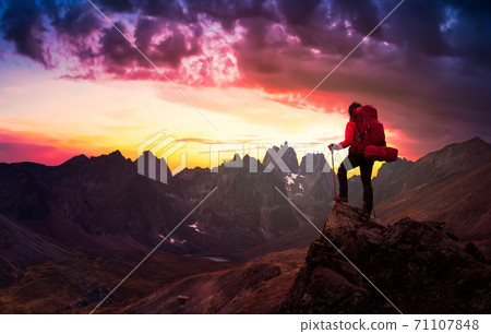 Woman Standing on Rocks looking at Scenic Mountain Peaks and Valley 71107848